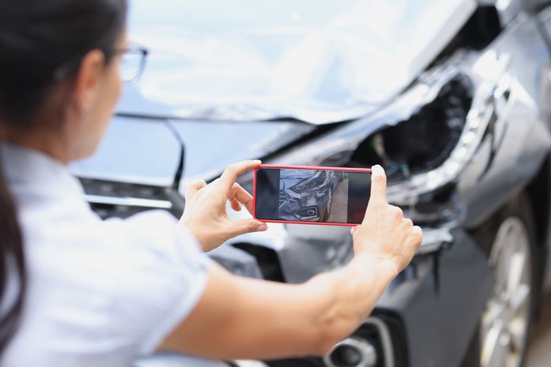 mujer sacando foto del faro roto de un coche