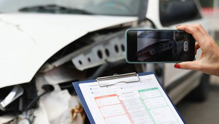 agende de aseguradora tomando fotos y anotando los daños de un coche